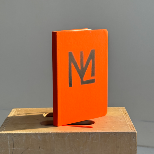 Orange notebook with the machiniste logo on an apple box 